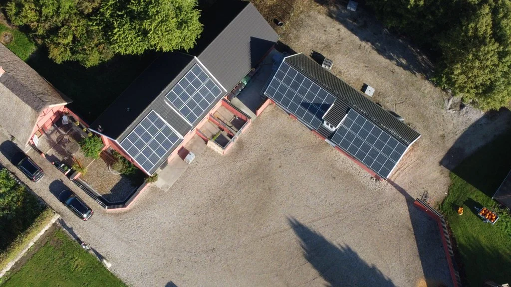 Dronefoto af ejendom med solcellepaneler på flere tagflader