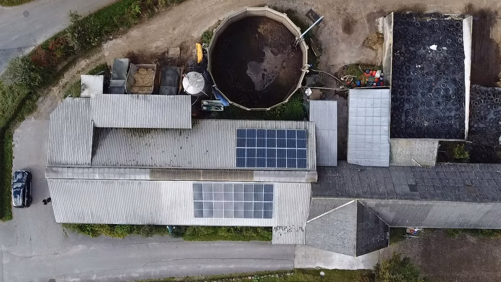 Dronefoto af gård med solcellepaneler og ovenlysplader på staldtag